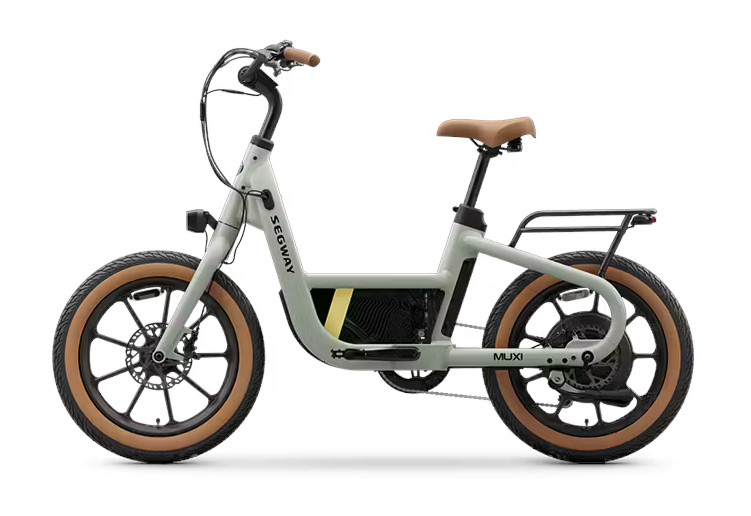 Product photo of the Segway MuXi ebike from the left side view. From this angle you can see the left side of the bike, from the tan wall front tire, the light on the fork, the curving handlebar, the main tube extending down from the head tube to then cradle the battery before continuing back towards the rear wheel, along the the tan wall rear tire, rear rack, and brown seat